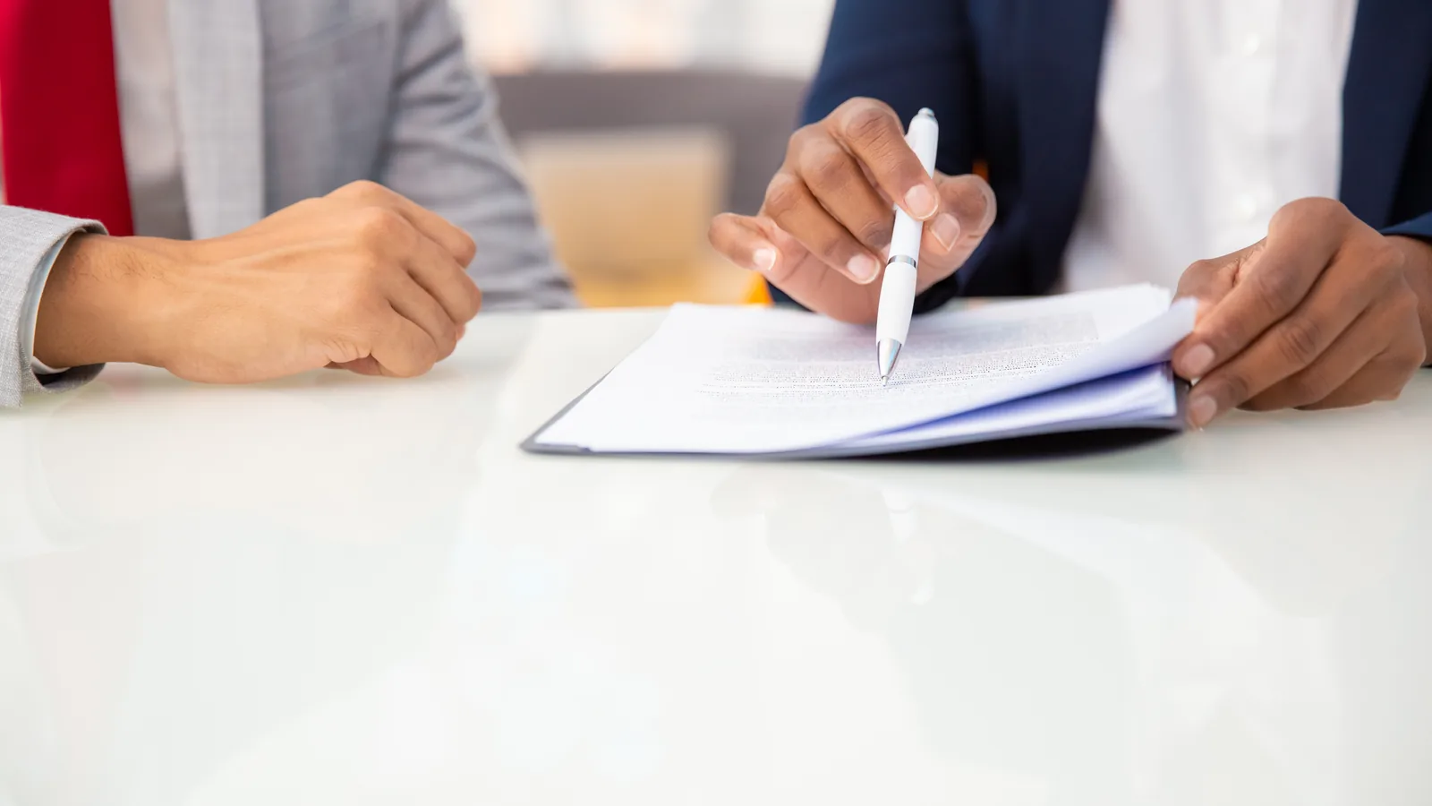 Two colleagues reading through a printed employment contract together at a desk.