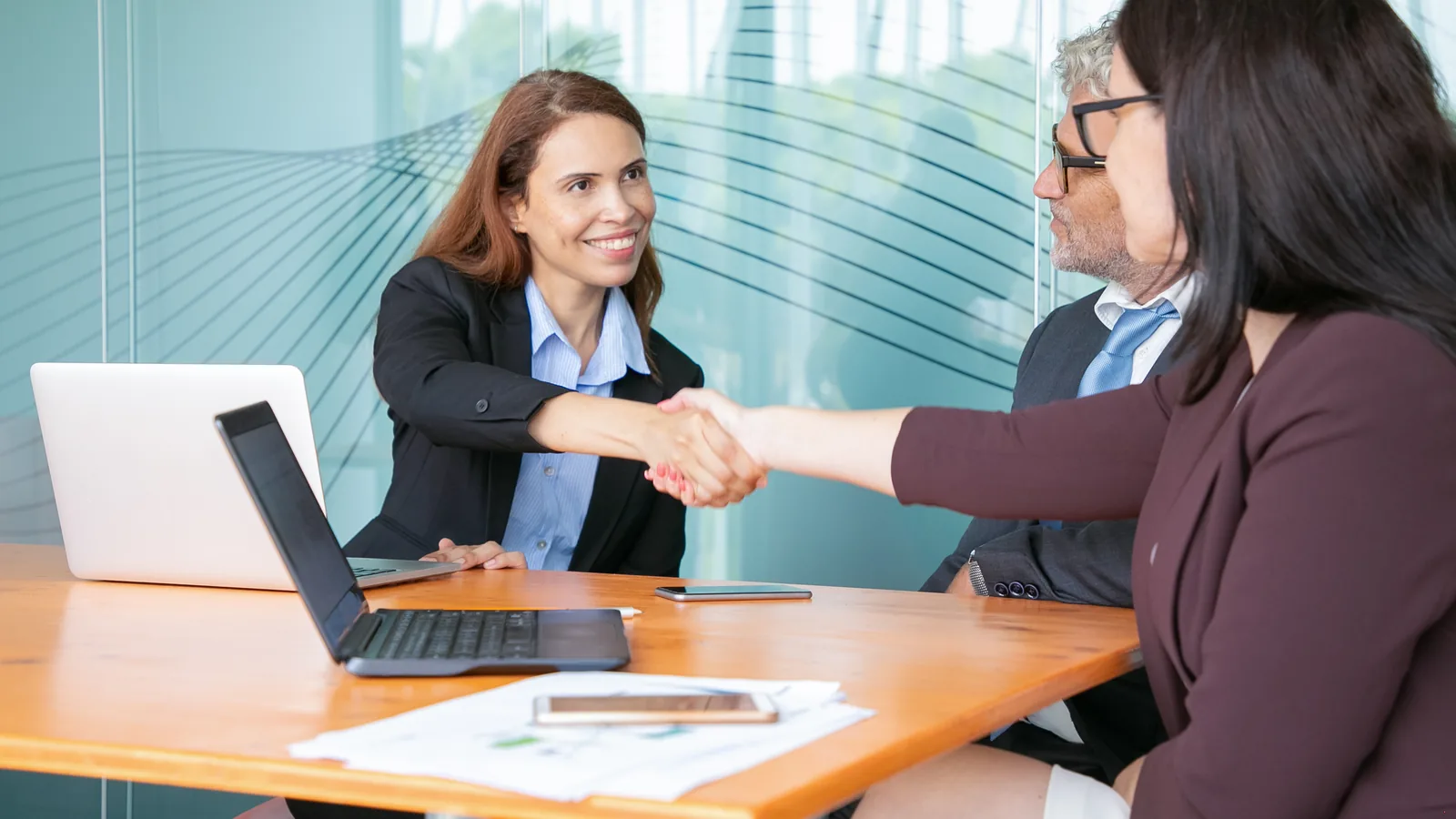 An HR manager meeting an employee across a table in a conference room.